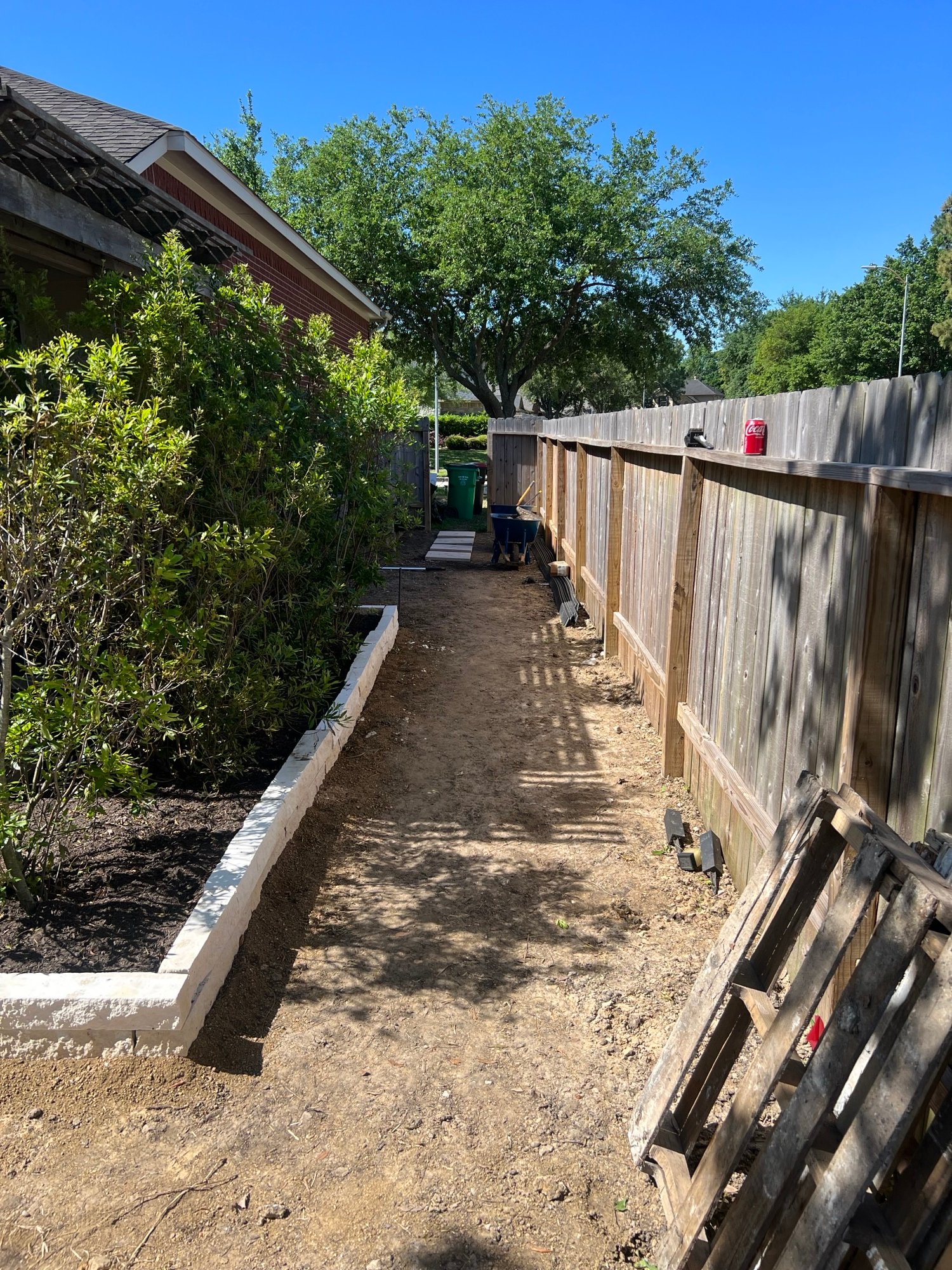 Backyard garden installation featuring white chopped stone edging and 45-gallon screening plants for privacy and aesthetic appeal in The Groves neighborhood in Summerwood, Tx
