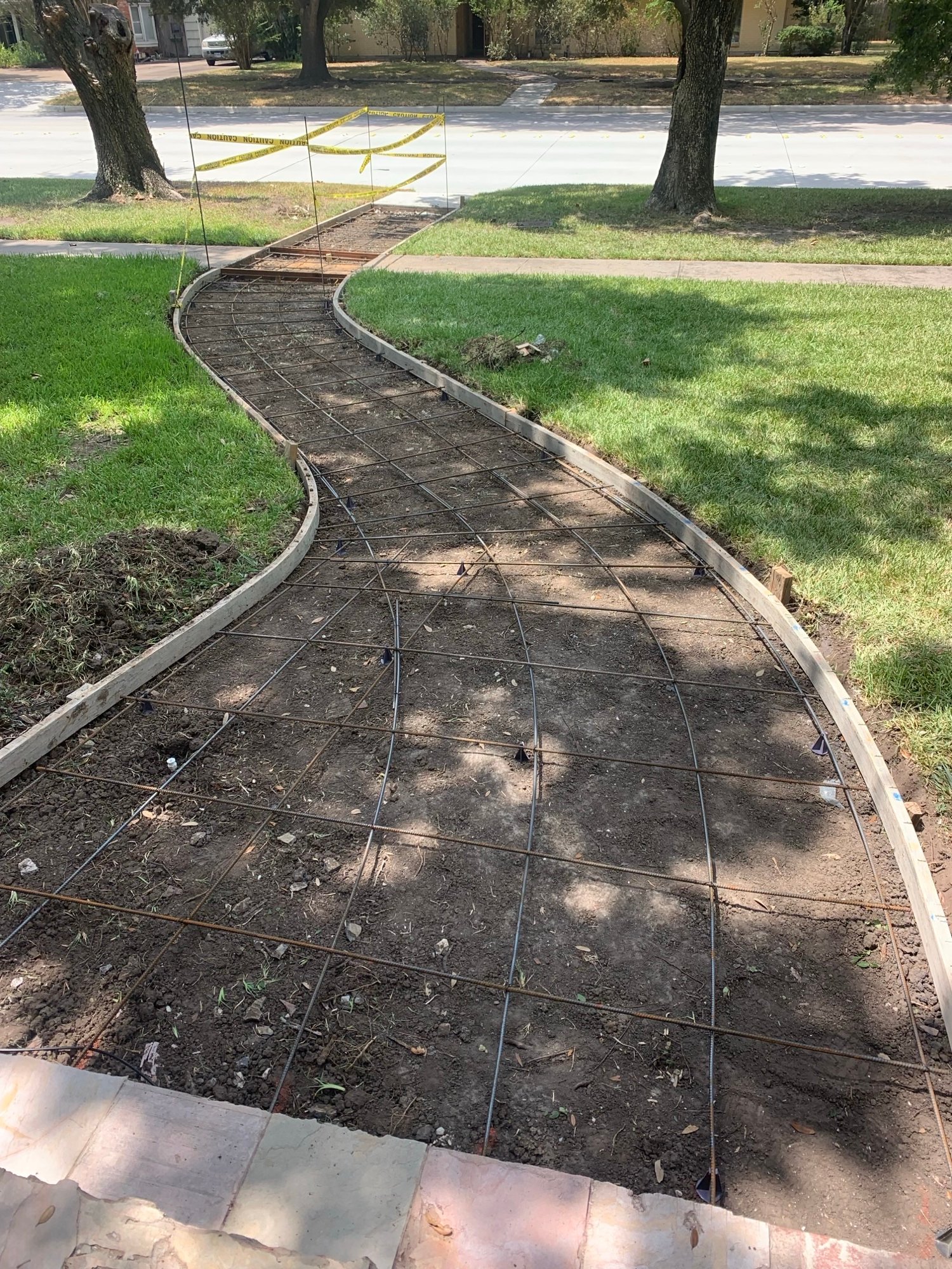 Concrete services underway for a curved front walkway installation, enhancing the entryway of a residential lawn.