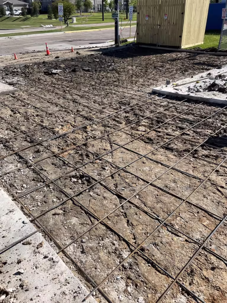 Repaired section of a small business parking lot in Houston with old concrete demoed and new rebar in place, showing Evergreen’s commercial concrete repair work.