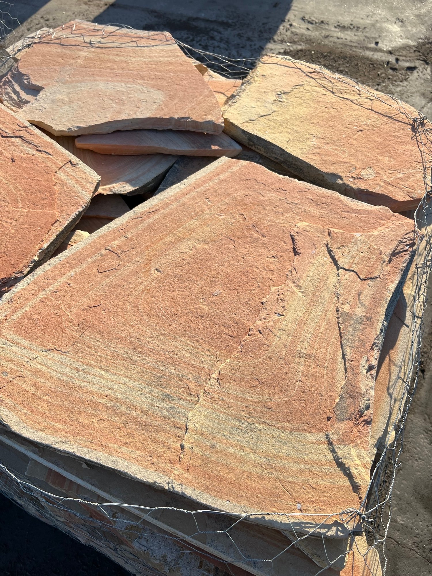 Close-up of flagstone featuring light brown, creamy brown, and red hues, highlighting natural textures and colors