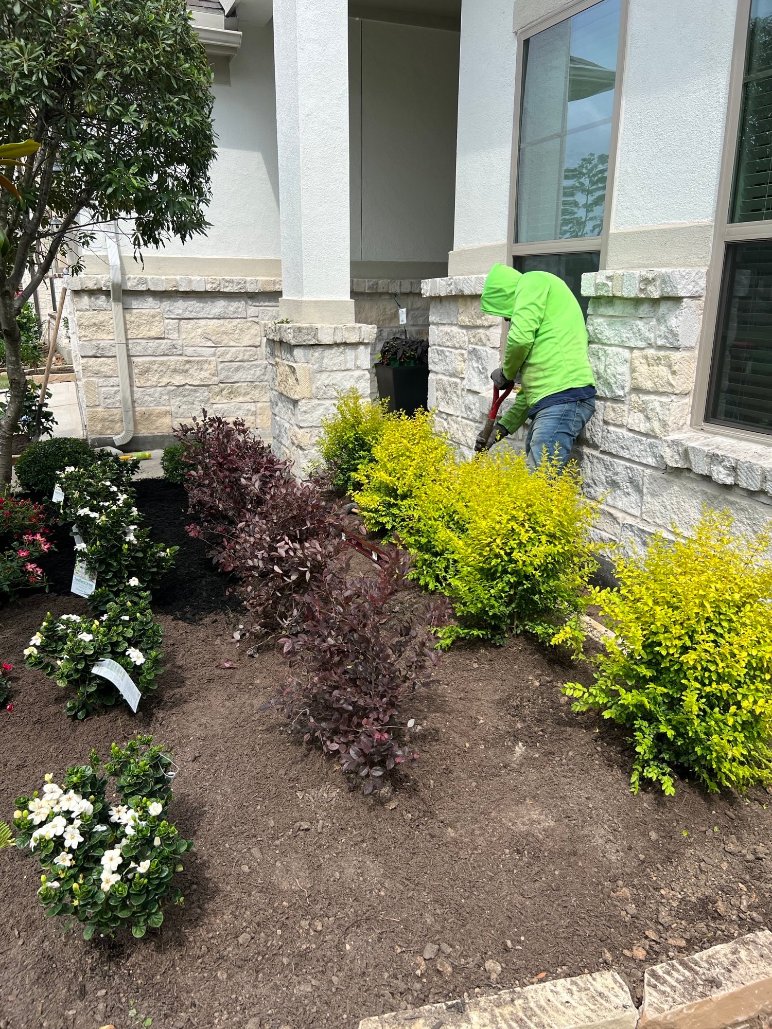 Man Landscaping in Humble, TX suburban home featuring stone and shrubs