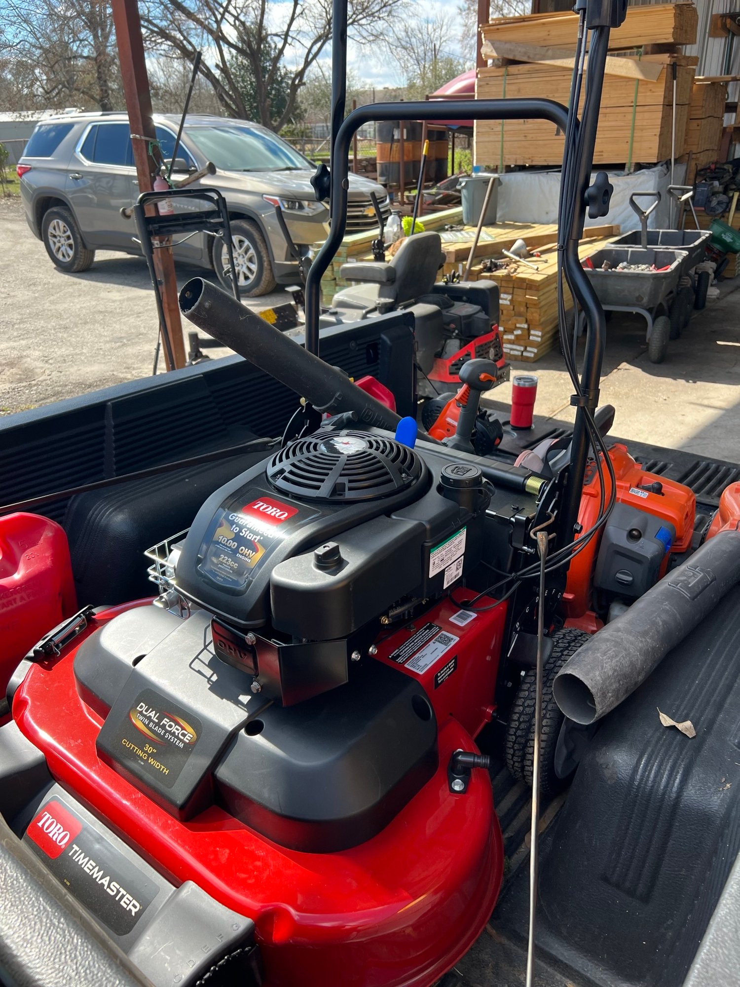 Mowing setup featuring mower, trimmer blower and gas tank on truck bed