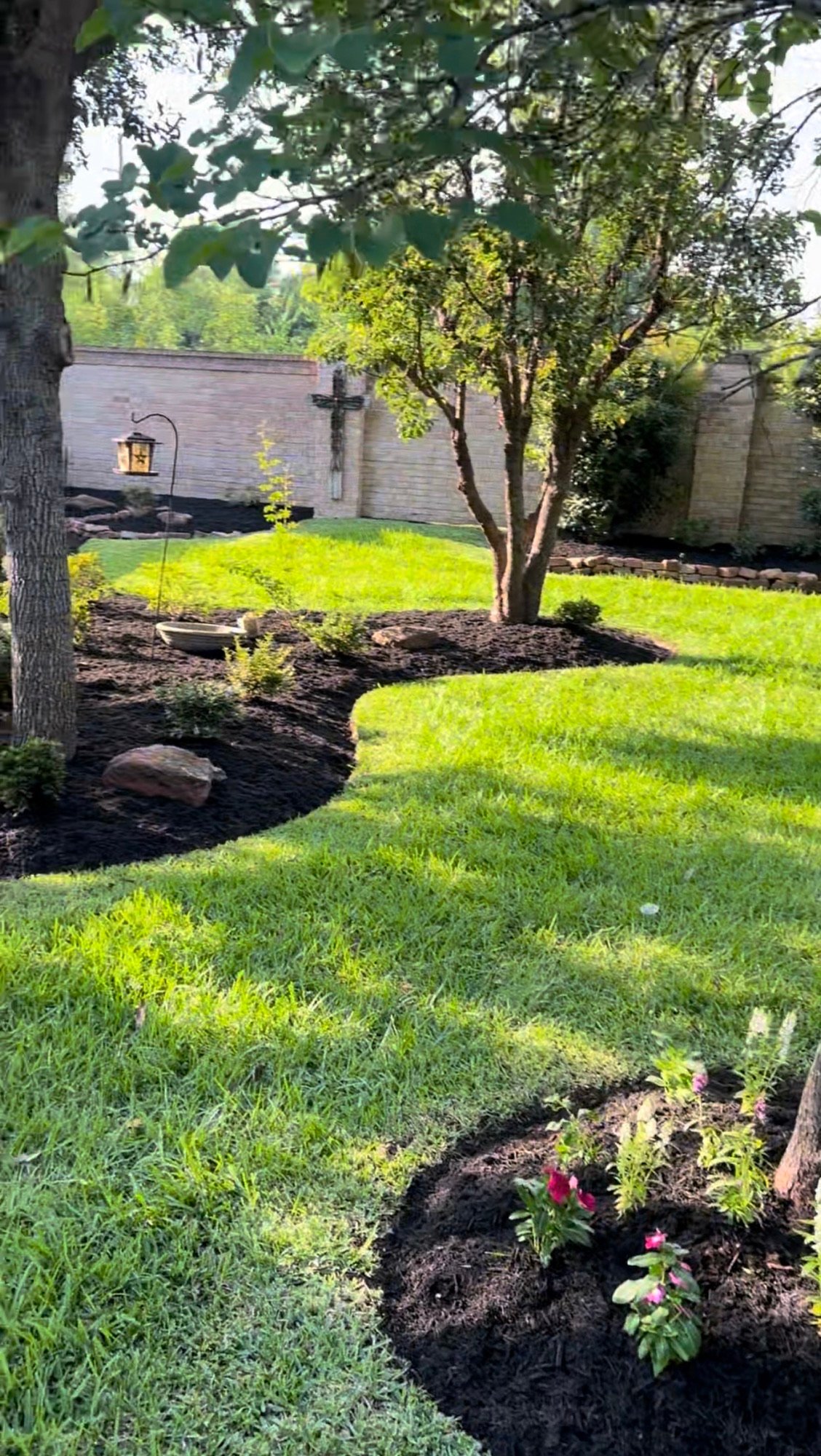 Close-up of backyard garden beds in Summerwood being mulched with rich, dark mulch for improved soil health and a polished look.