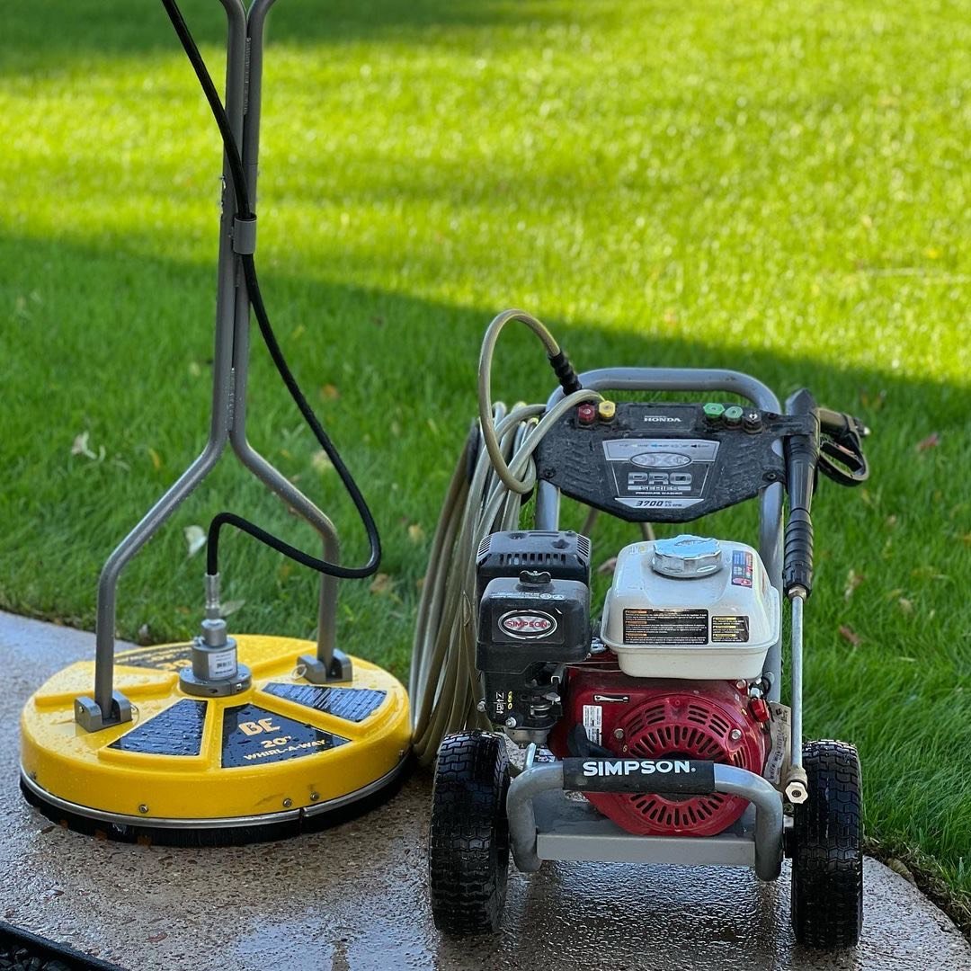 Pressure washing equipment on a freshly cleaned walkway with a green lawn in the background, taken in Baytown, Texas
