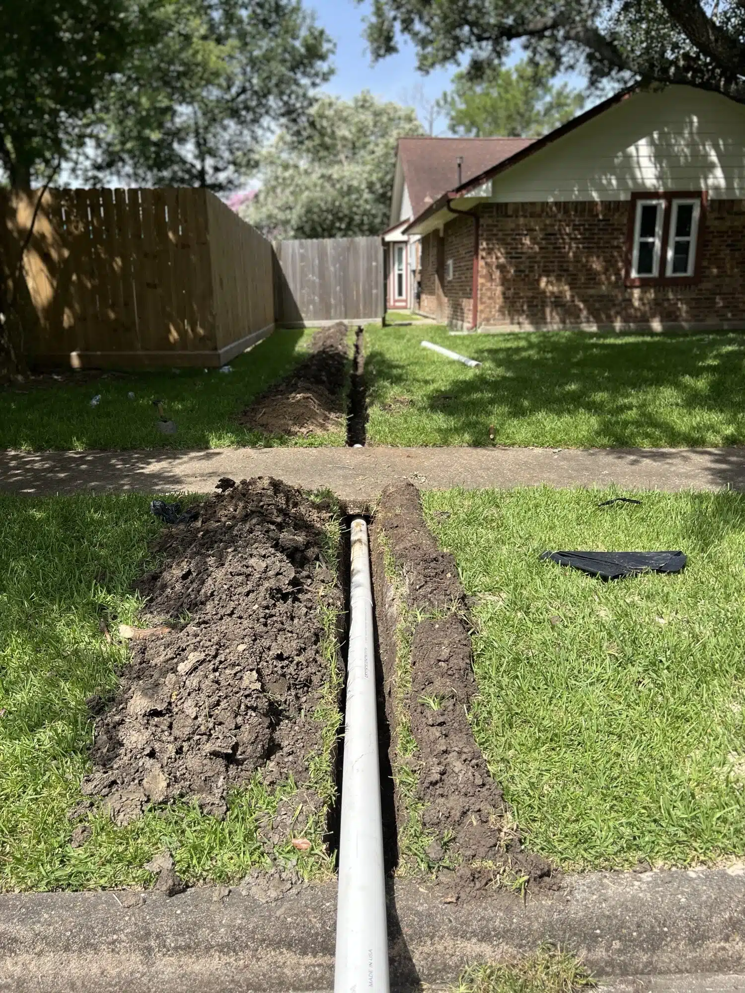 Evergreen Outdoor Services crew digging a drainage trench in Houston clay
