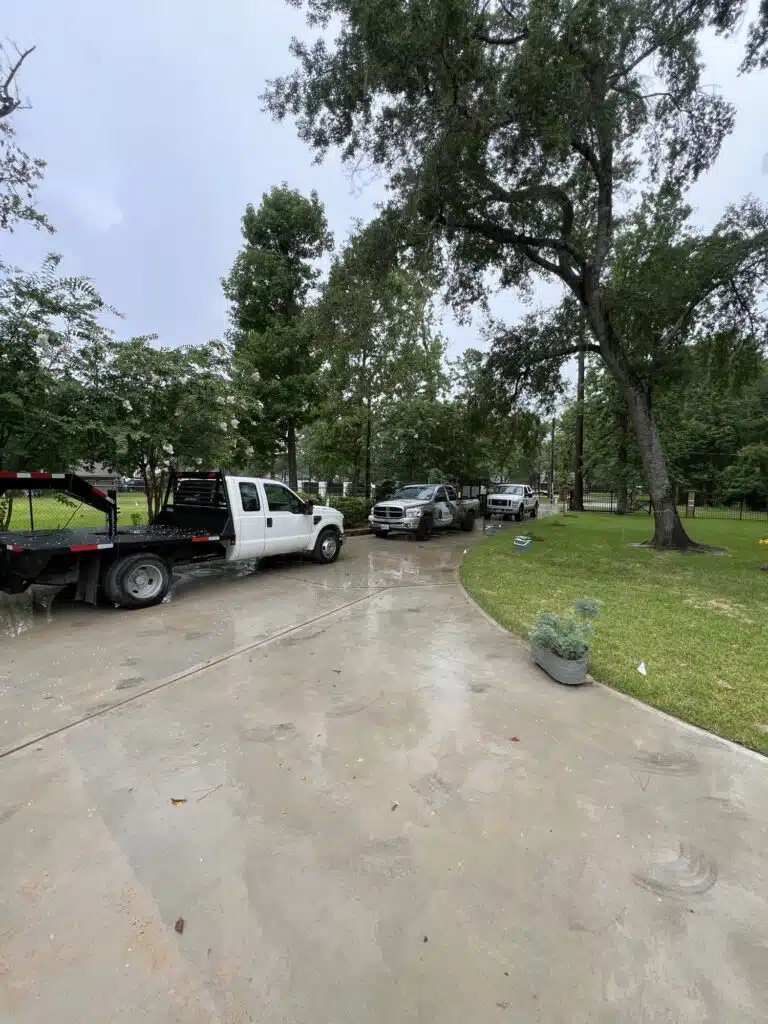 Crew vehicles on-site during a residential lawn leveling project in Houston, preparing to correct uneven turf using sand and grading techniques on a rainy day.