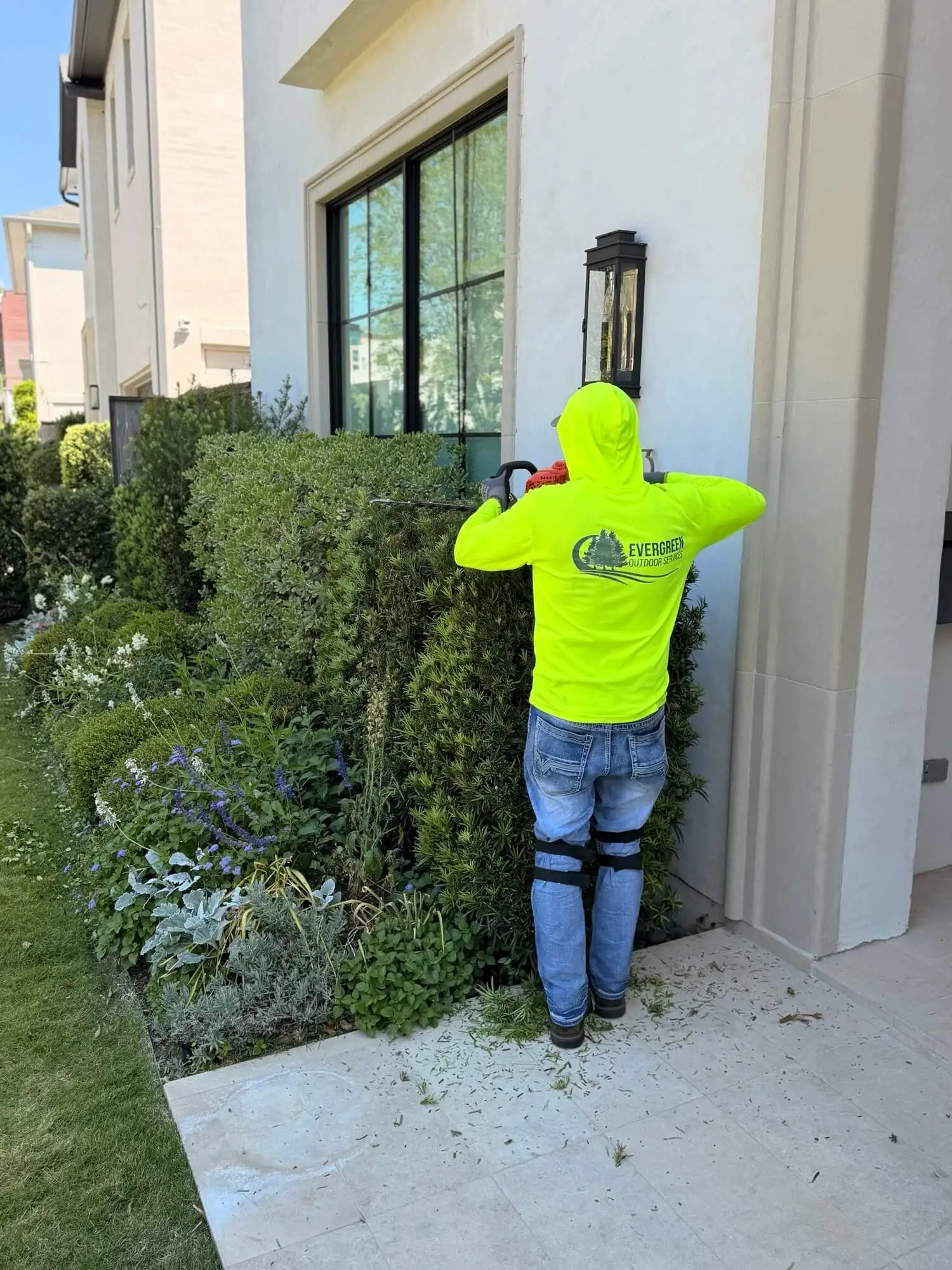 Evergreen Outdoor Services performing shrub trimming and residential property cleanup work in Houston