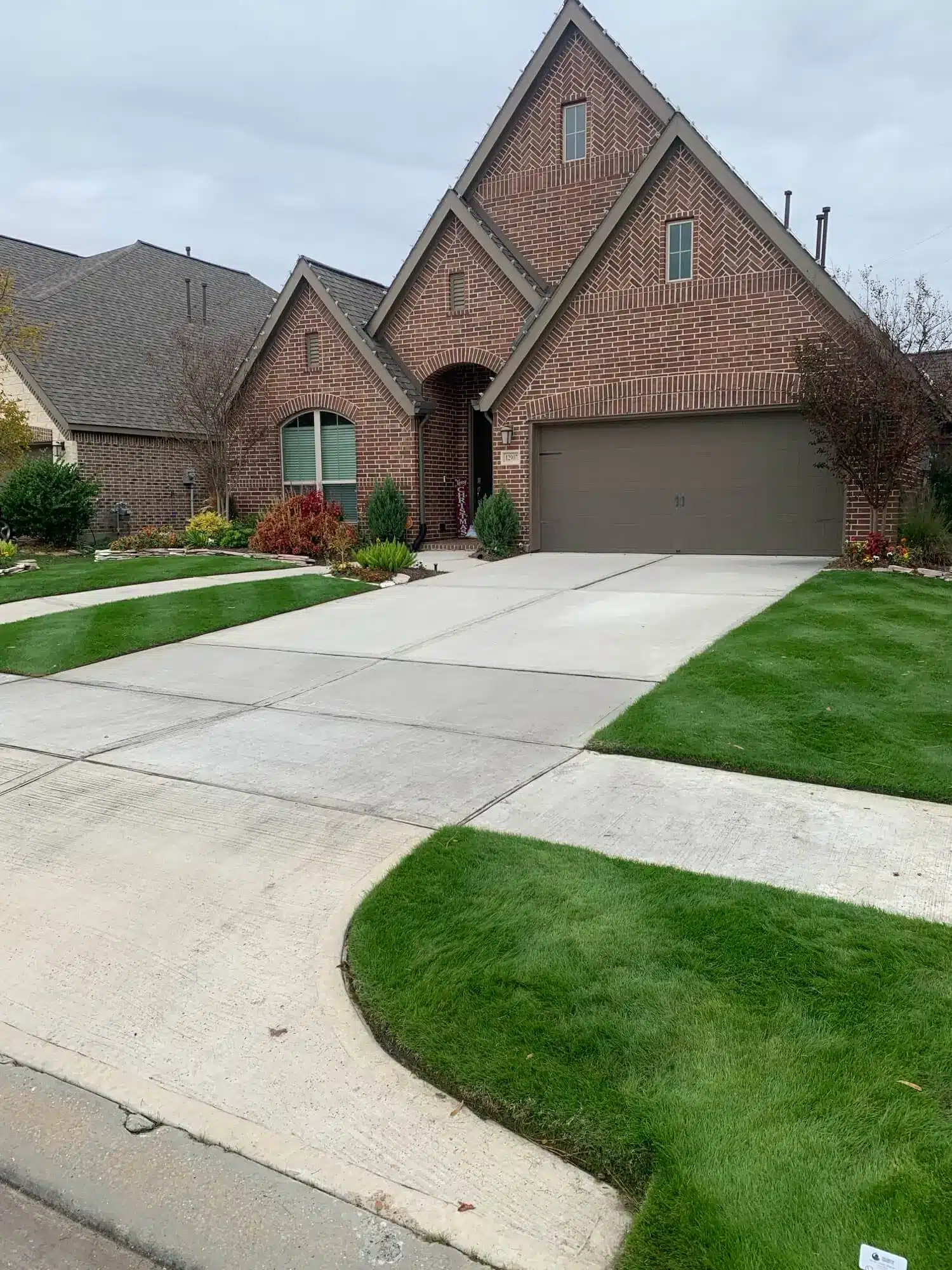 Brick home in The Groves near Summerwood with a lush green lawn, sharp edging, and a clean concrete driveway