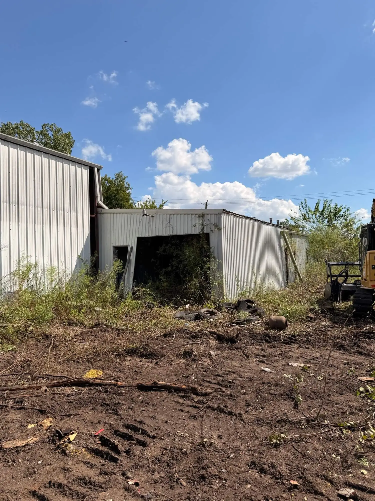 Land clearing in progress around an overgrown warehouse property in Houston